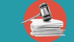 Stack of papers and gavel against teal and orange background